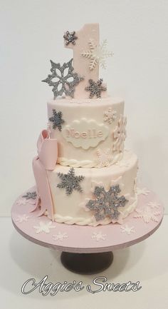 a three tiered cake decorated with snowflakes and stars is on a pink plate