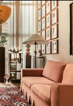 a living room filled with furniture and pictures on the wall next to a lamp in front of a window