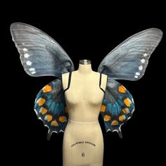 a female mannequin with blue and orange butterfly wings on it's back