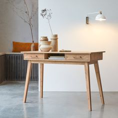 a wooden table with two vases on it and a lamp next to the table