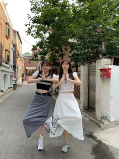 two young women standing next to each other in the street