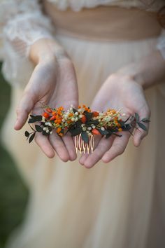 a woman is holding out her hands with flowers on it and a comb in the palm