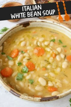 a white bean soup with carrots and parsley in a bowl next to bread