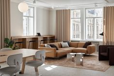 a living room filled with lots of furniture and windows covered in draping curtains