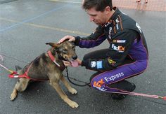 a man kneeling down next to a dog with a leash on it's neck