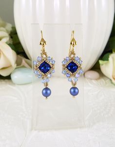 "Woven Earrings Crystal and Pearl Sapphire Blue These sapphire blue crystal chaton stones are hand woven with tiny golden seed beads and light Light Sapphire shimmer crystals featuring a Swarovski dark blue iridescent pearl drop.  They measure .5\" across and approximately 1.75\" from the top of the decorative latch back hook style style ear wires. A beautiful, petite style earring. Design by Cathy Andrews. https://www.etsy.com/shop/IndulgedGirl" Blue Drop Earrings With Bead Caps, Elegant Blue Jewelry With Bead Caps, Elegant Blue Beaded Earrings, Woven Earrings, Iridescent Pearl, Petite Style, Light Sapphire, Handmade Jewelry Designs, Earrings Crystal