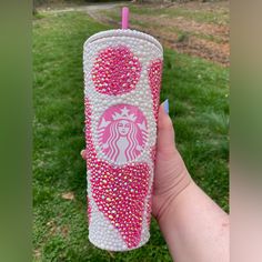 a hand holding a pink and white starbucks drink