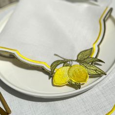 a white plate topped with two lemons on top of a cloth covered placemat