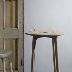 a table with two glasses sitting on it next to a chair and door in the background