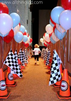 a little boy standing in front of a bunch of balloons and checkered cone cones