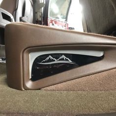 the interior of a vehicle with its door handle and side view mirror showing mountains on it