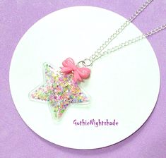 Here we have a lovely Star & Bow Shaker Necklace which is made on lovely silver plated chain to a length of 51cms (20 inches) although you can choose different lengths from the drop down menu.   This delightful Kawaii Necklace is made with a PVC Shaker Star Pendant which measures 7 x 7 cm and has a 3 x 2cm Pink Acrylic Bow on top that is full of sequins .  This Unique Necklace closes with a lobster clasp.  An ideal Summer Necklace or all year round for a Pastel Goth lover. I also have a matching Silver Star Charm Necklaces For Party, Silver Star-shaped Charm Necklaces For Party, Kawaii Silver Handmade Necklaces, Kawaii Handmade Silver Necklaces, Handmade Silver Kawaii Necklaces, Handmade Silver Necklaces In Kawaii Style, Silver Harajuku Jewelry For Party, Silver Harajuku Style Party Jewelry, Cute Silver Charm Necklaces For Party