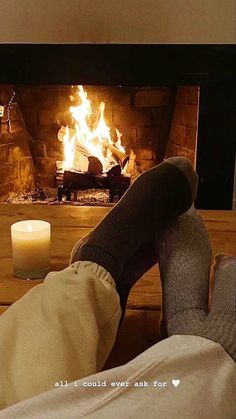 two people sitting in front of a fireplace with their feet up on the coffee table