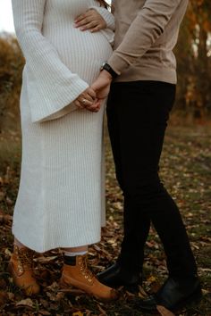 a pregnant woman and man standing next to each other with their hands on their belly