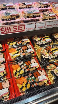 a display case filled with lots of different types of sushi and other foods in plastic containers