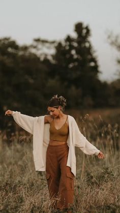 a woman standing in a field with her arms outstretched