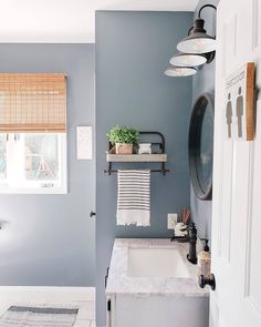 a bathroom with blue walls and white counter tops, hanging lights above the sink area