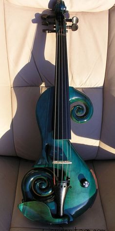 a green violin sitting on top of a white couch next to a pillow and chair