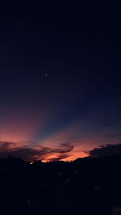 the sun is setting over some hills with trees in the foreground and an airplane flying overhead