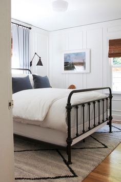 a bed sitting in a bedroom next to a window on top of a hard wood floor