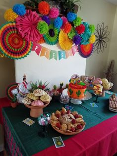 a table topped with lots of desserts and paper fan decorations on top of it