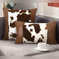 two brown and white pillows sitting on top of a couch next to a coffee cup