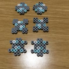 four pieces of black and blue beads on a wooden table with holes in the middle