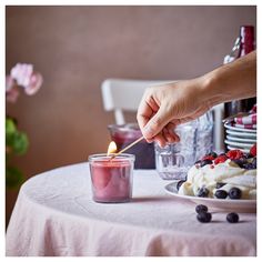 a person lighting a candle on top of a table next to plates and cups filled with food