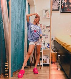 a woman standing in front of a mirror with her hand on her head and wearing pink shoes