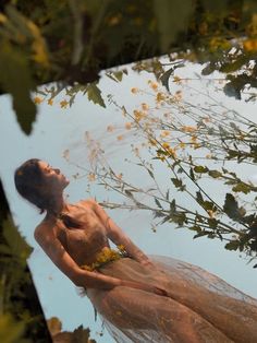 a naked woman is floating in the water with yellow flowers on her chest and head