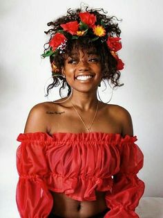 a woman wearing a red top with flowers in her hair