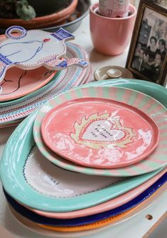 there are many plates on the table and one is pink, blue, green and white