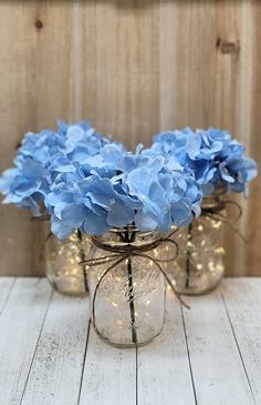 three mason jars with blue flowers in them