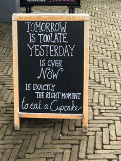 a sign that is on the side of a brick road saying tomorrow is today, yesterday is over now is exactly the right moment to eat a cupcake