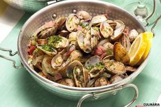 clams in a pan with lemon wedges and parsley on the side, ready to be eaten