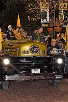 a group of people riding on the back of an old fashioned truck in a parade