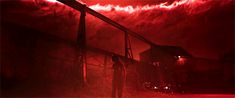 a man standing in front of a red smokestack at night with his back turned to the camera