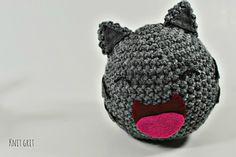 a crocheted stuffed animal with a pink nose and tongue sticking out from it's mouth