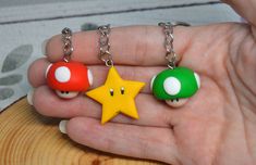 two keychains with mario and luigi on them in the palm of a person's hand