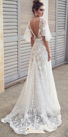 a woman in a wedding dress standing on the sidewalk with her back to the camera