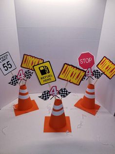 there are four traffic cones and signs on the white tablecloth with black and yellow stripes