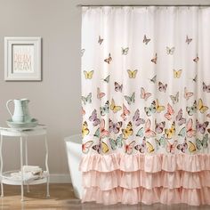 a shower curtain with butterflies on it and pink ruffles around the edges, in a bathroom