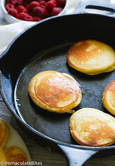 pancakes in a skillet with raspberries on the side