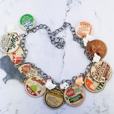 a bunch of different types of bottle caps on a silver chain bracelet with an animal charm