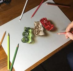 three ceramic animals are sitting on a piece of paper with colored pencils next to them