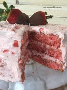 a strawberry cake with one slice cut out and two strawberries on top