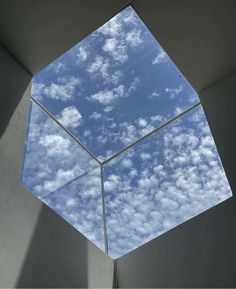 the sky is reflected in an octagonal glass window on top of a concrete structure with white walls