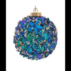 an ornament with blue and green flowers on it's side, hanging from a gold chain