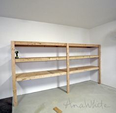 an empty room with shelves and tools on the floor in front of white painted walls