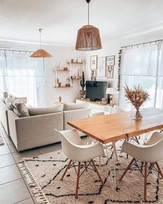 a living room filled with furniture and a wooden dining table surrounded by white couches